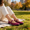 Mujer usando ballerinas barefoot burdeo en un parque, calzado respetuoso para uso urbano.
