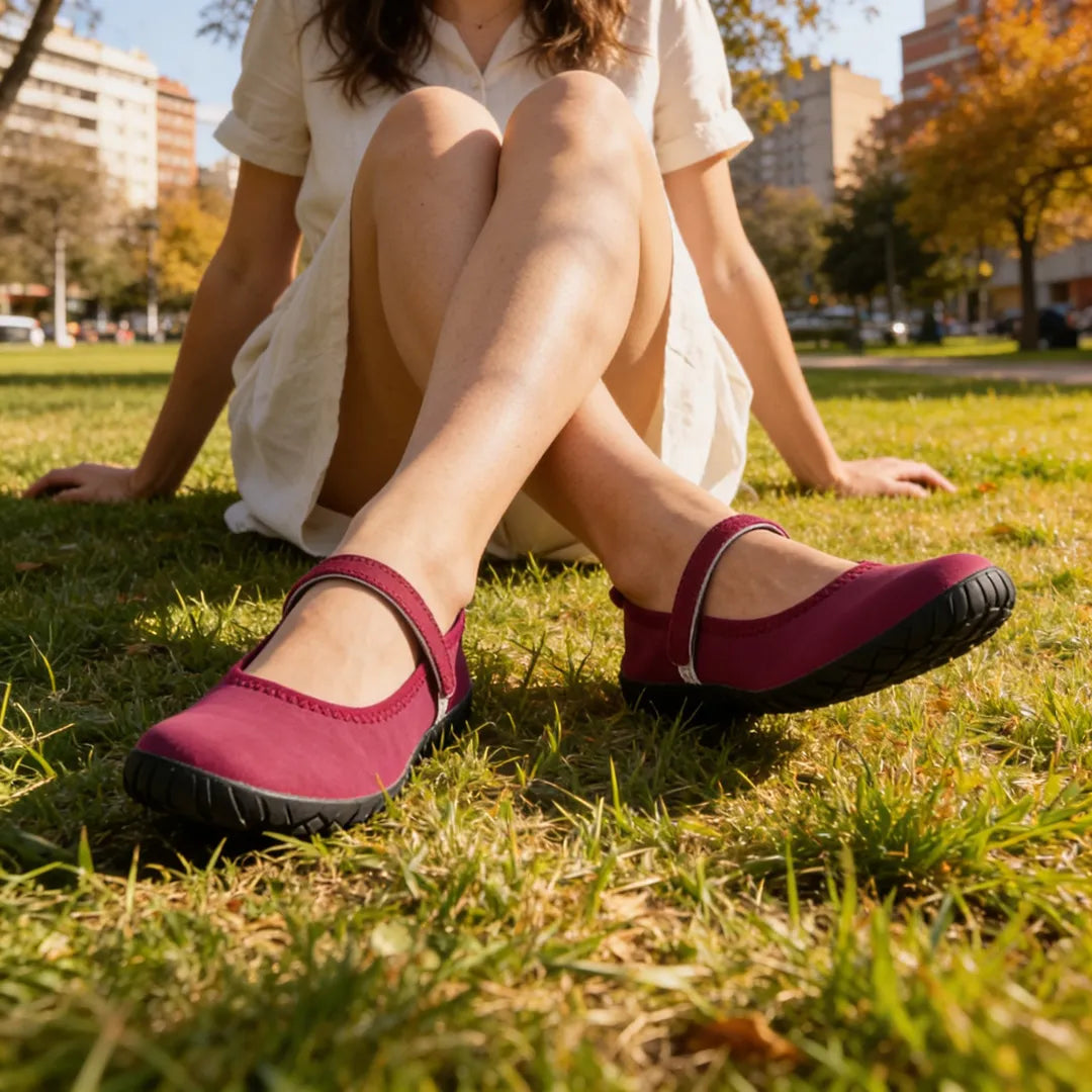 Persona relajada usando zapato barefoot burdeo, destacando la suela flexible y tracción en el parque.